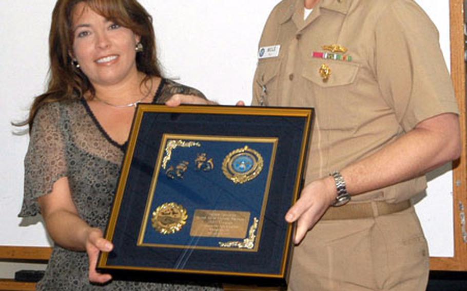 Mayra Kent, a volunteer with the 18th Medical Group from Kadena Air Base, receives the 2003 Civilian Award of Excellence from Capt. Dale Molé, the executive officer of the U.S. Naval Hospital Okinawa. Kent received the award for coordinating a bimonthly blood drive at the 18th Medical Group that benefits the Armed Services Blook Bank.