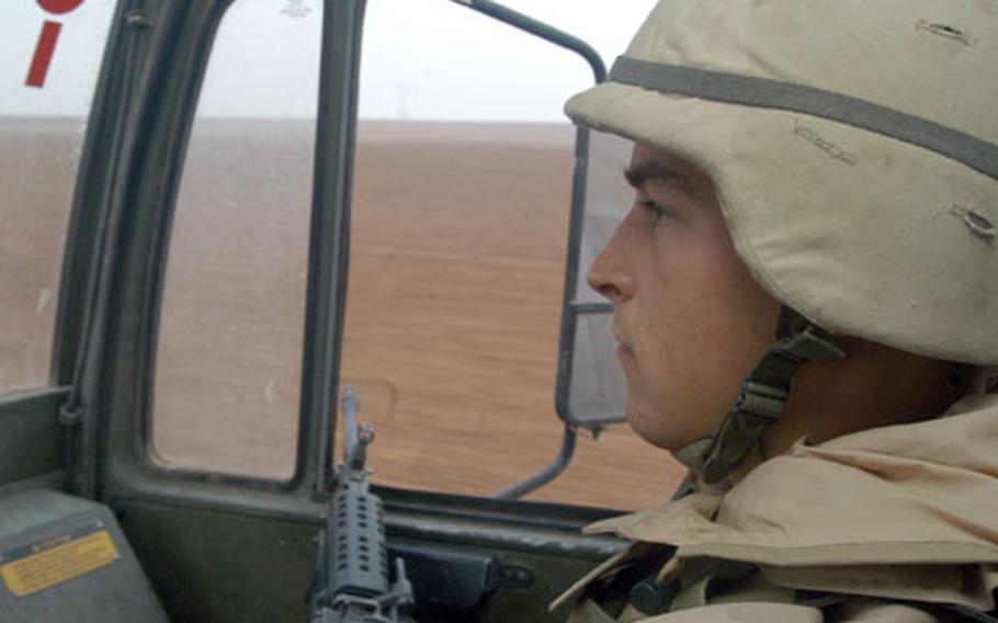 With nothing but vast open desert surrounding him, Pfc. Greg Schlaht, 20, from Aberdeen, Wash., pulls security from the passenger seat of a a 2½-ton truck during a four-hour trip to remote bases near Qayyarah Air Field in northern Iraq. Schlaht is an ammunition specialist for the 2nd Battalion, 320th Field Artillery Regiment of the 1st Brigade, 101st Airborne Division.