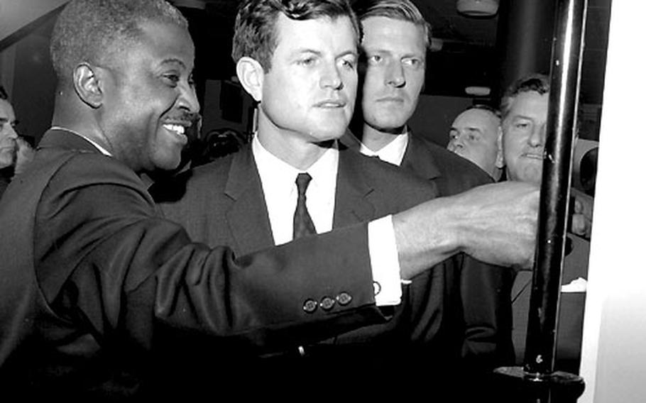 Sen. Edward M. Kennedy, D-Mass., is given a tour of Amerika Haus' 20th-anniversary exhibit by the consulate cultural center's director, Osborn T. Smallwood, in May, 1966.