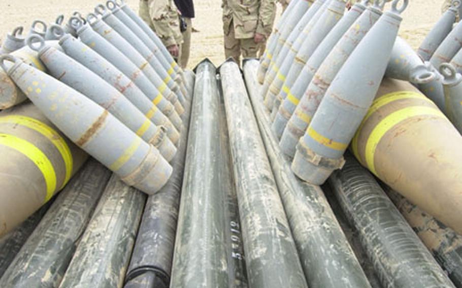 Soldiers look over the pile of Iraqi artillery shells, bombs and missiles being set up for demolition.