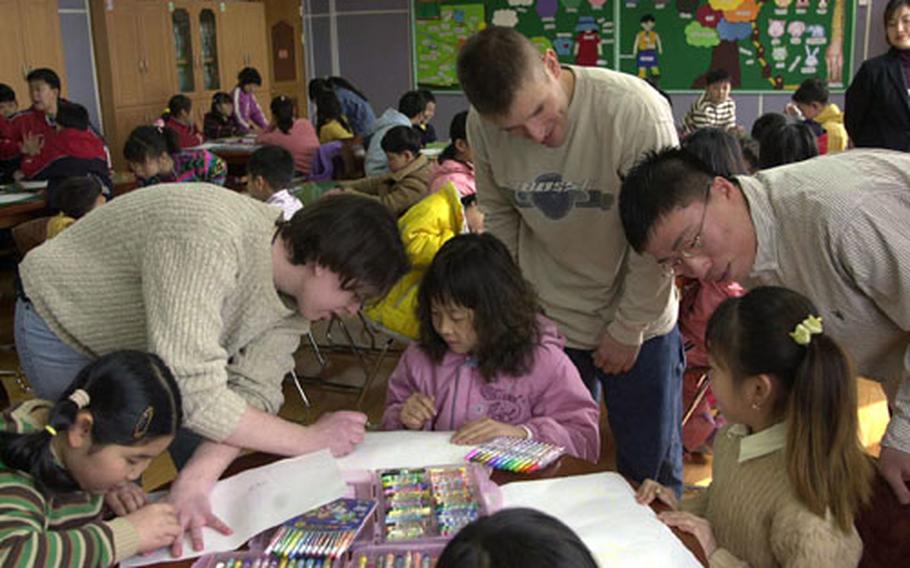 Army Spc. Abigail Lineau, Staff Sgt. David Mello and Pfc. Huh Min Jung, with D. Co., 5th Battalion, 5th Air Defense Artillery Regiment, work with South Korean students during an English-language lesson at an elementary school near Camp Casey, South Korea.