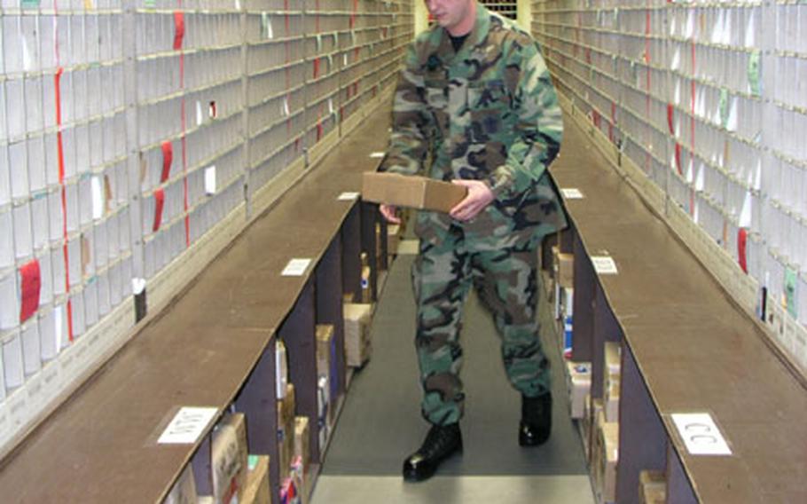 At Osan Air Base, South Korea, Airman Anthony Powell takes from the shelf a parcel being picked up by a customer waiting at the service window.