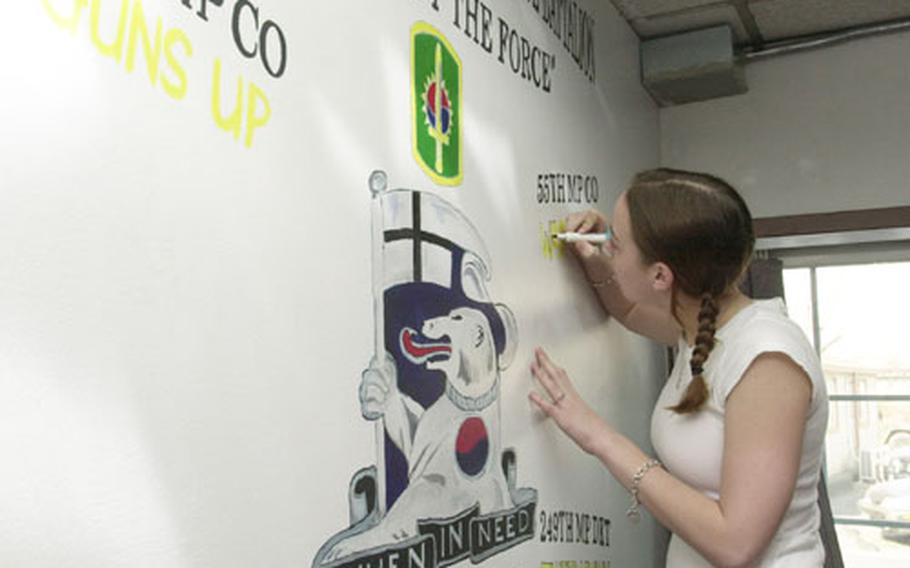 Seoul American High School junior Sara Wilson accents the mural she helped create for the 94th Military Police Battalion at Yongsan Garrison.