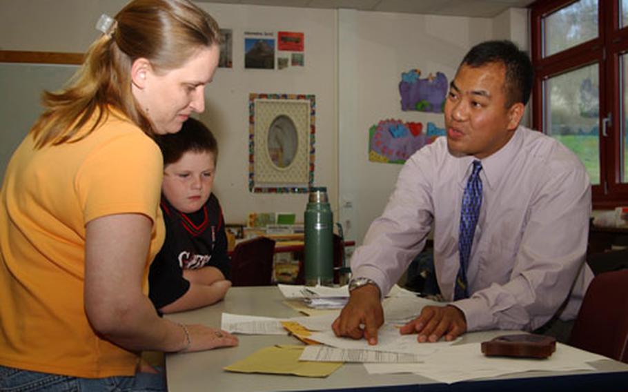 Stephanie Graber and her son, Trevor, listen to third-grade teacher John Tayag, during a parent-teacher conference Friday at Butzbach Elementary School. Graber is the legal guardian of a student in Tayag&#39;s class whose father is deployed with the 1st Armored Division.