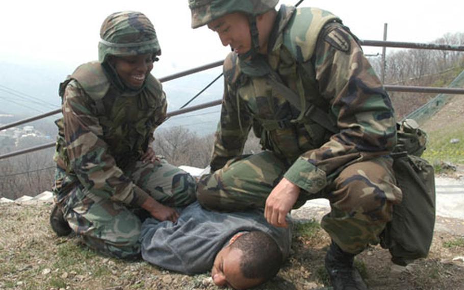 Pfc. Lateidria Mitchell and Pfc. Lee Jin-ho detain Pfc. Paris Woods, who played the role of an infiltrator at Madison Site, a microwave signal relay site on top of Kwangyo Mountain near Suwon. The hilltop site commands a great view of the surrounding area, although Pfc. Woods isn&#39;t particularly in a position to enjoy that view.