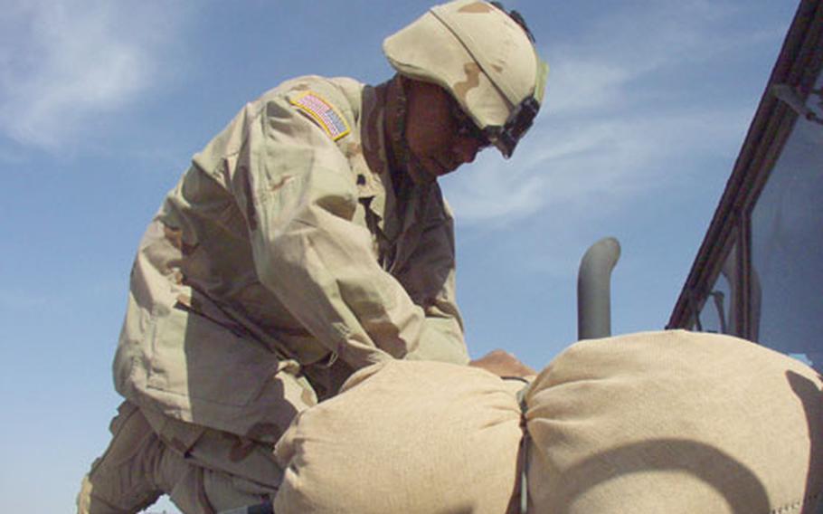 Spc. Francisco Sloan, 24, of Laredo, Texas, secures sandbags to his 5-ton heavy equipment truck at Camp New York, Kuwait. Sloan, a soldier with the 1st Infantry Division&#39;s 299th Forward Support Battalion, and the rest of the Big Red One are preparing vehicles for a convoy ride north to Iraq.