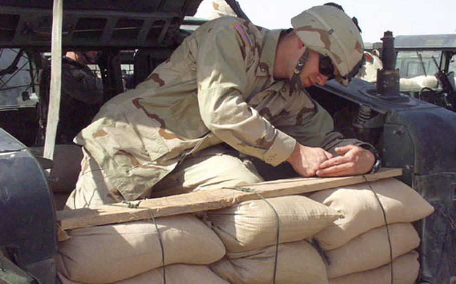 Pfc. Bryan Heiss, 20, of Harrisburg, Pa., attaches sandbags to the cargo bay of Humvee from the 1st Infantry Division’s Task Force 1-77, from Schweinfurt, Germany.