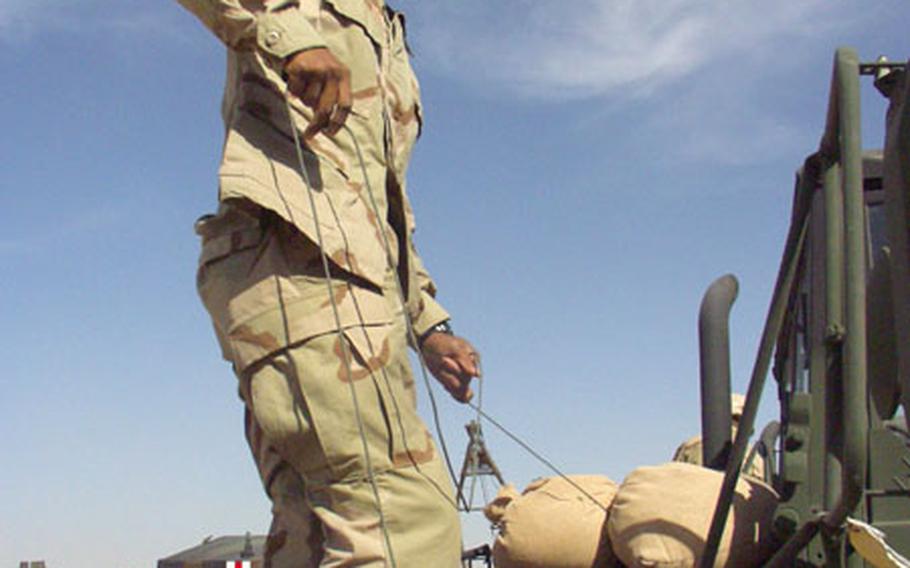 Spc. Francisco Sloan, 24, of Laredo, Texas, secures sandbags to his 5-ton heavy equipment truck at Camp New York, Kuwait.