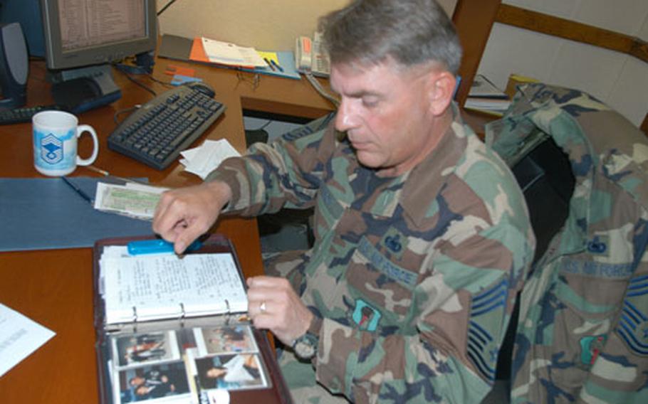Chief Master Sgt. Brett E. Allison pages through photos of his family. The 35th Operations Group superintendent at Misawa Air Base, Japan, will commission his daughter, Sherry, as an officer into the Air Force on May 15. The Allisons found a legal loophole that allows an enlisted member to administer the officers&#39; commissioning oath.