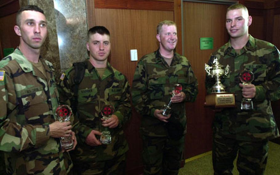 Spc. Jonathan Waldron, Pfc. Thomas Vander, Sgt. Gregory Bodin and Pfc. Andrew Mach-Miller, all of the 702nd Main Support Battalion at Camp Nimble, hold glass trophies Friday for placing first in a water purification competition held last week.