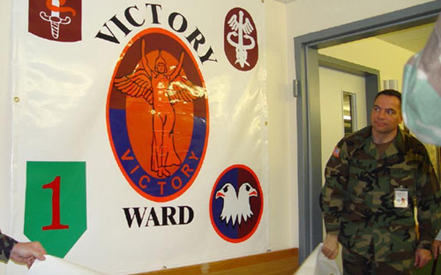 Sgt. 1st Class Tom Goodrow of the 348th General Hospital, the ward master for Victory Ward helps unveil a banner during last week&#39;s official opening ceremony of the ward at the Würzburg Army Hospital.