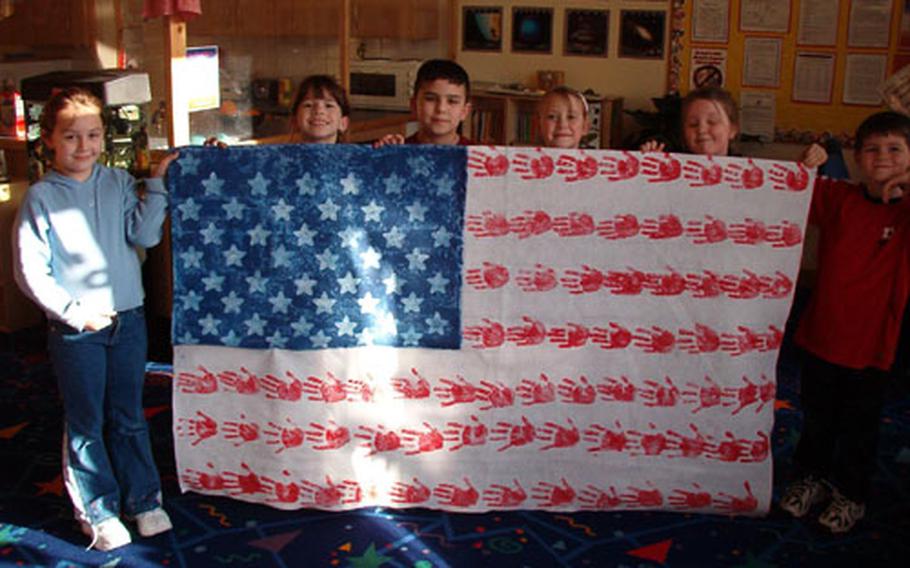Children in the School Age Program at RAF Mildenhall Youth Center, England, show off the flag they made for troops in Iraq.