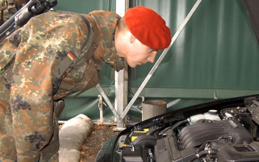 A German army soldier of Panzer Artillerie Batallion 515 from Kellinghusen, Germany, checks under the hood of a car entering Cambrai Fritsch Kaserne in Darmstadt, Germany.
