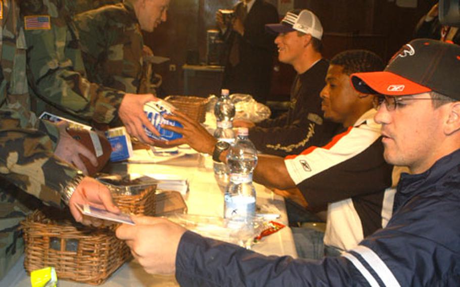 Keith Brooking, linebacker for the Atlanta Falcons, Warrick Dunn, running back for the Falcons, and Todd Heap, tight end for the Baltimore Ravens, sign autographs for troops of the 1st Armored Division who are scheduled to head back to Iraq in the next several weeks after an extension was made on their unit.