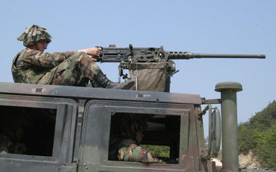 Pfc. Kelly Stewart fires a machinegun atop an HMMWV in Warrior Valley on Thursday.