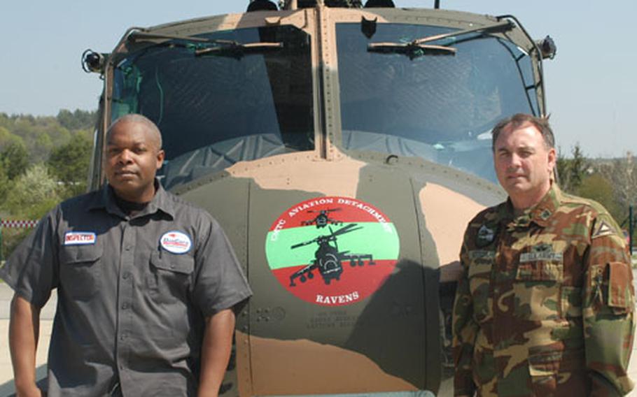 Archie Smith, left, site supervisor for aviation services contractor DynCorp, and Chief Warrant Officer 4 Douglas Hettler, aviation maintenance officer for the Combat Maneuver Training Center Aviation Flight Detachment in Hohenfels, Germany, stand near one of the UH-1 Huey helicopters the unit maintains.