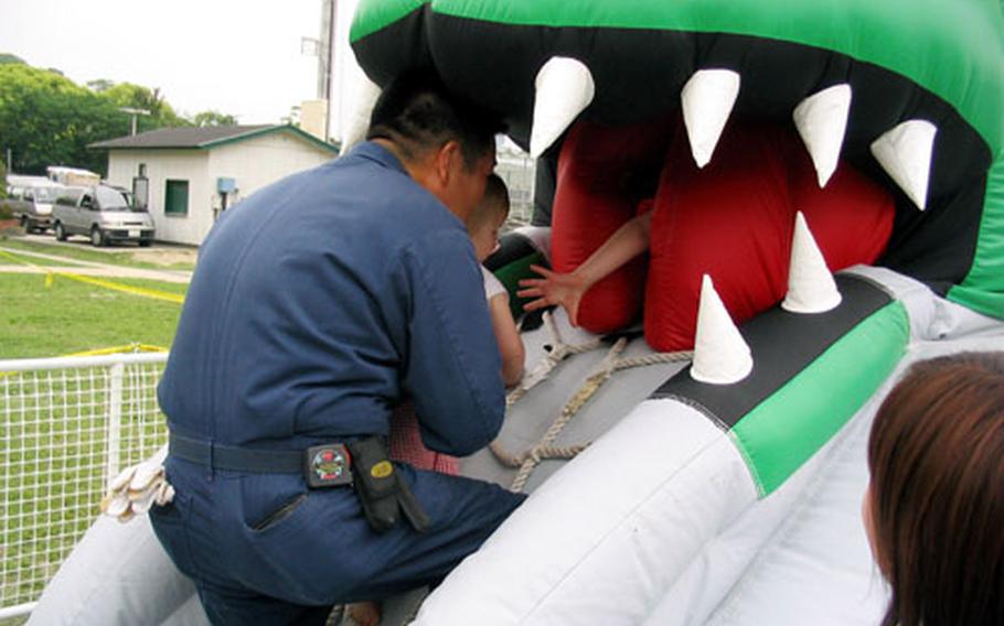 An employee manning the Dragon air toy helped feed the big lizard by helping this little fellow into the fire-breather&#39;s big mouth on Saturday in Nimitz Park at Sasebo Naval Base&#39;s 2004 Armed Forces Day Sports and Fitness Program.