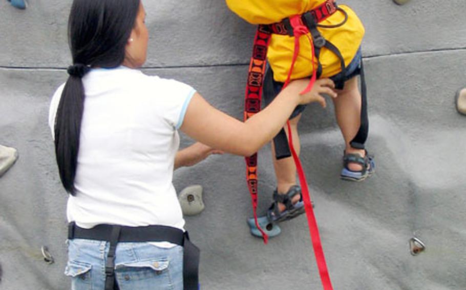 Two-year-old Michael Jones tries his best to get a good start on the rock-climbing wall with help from Michelle Jones, his mother, in Nimitz Park Saturday during the MWR-sponsored 2004 Armed Forces Day Sports and Fitness Program.