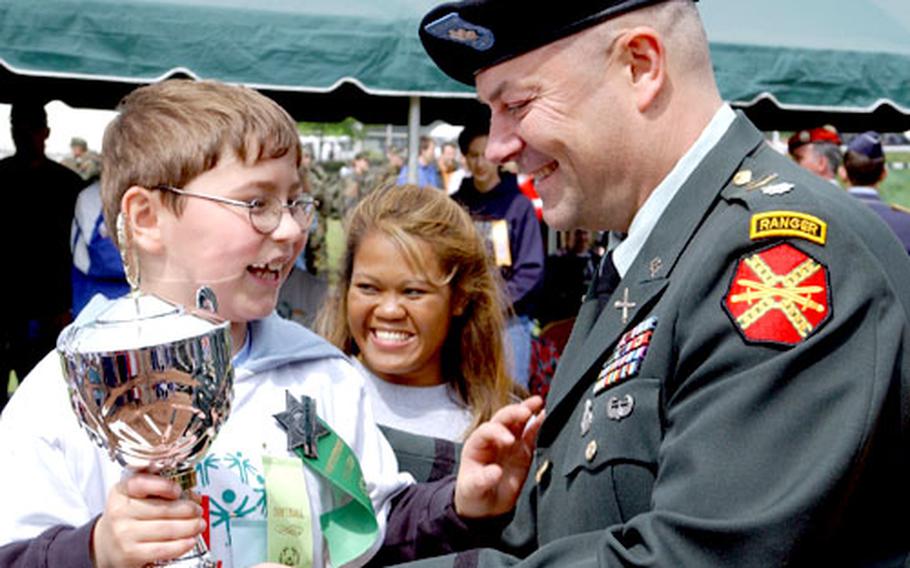 Lt. Col. David Hall, 415th Base Support Battalion commander, presents Wladimir Moser, 8, with the Sarah Bican Inspirational Athlete trophy.