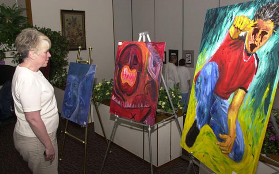 Jan Noyes studies a painting Tuesday night at an exhibit featuring Yokota High School&#39;s top artists at Yokota Air Base, Japan. The exhibit was open to the public and seniors Jason Correll, David Hale, Sarah Hannon and Mike Garcia all showed work.
