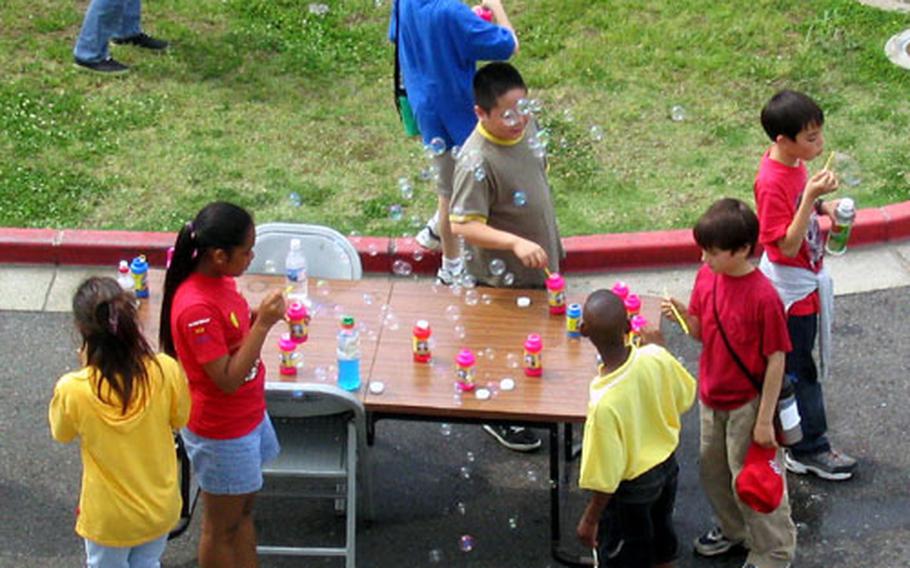 Sasebo Elementary School pupils gather around a makeshift bubble station as their floating creations float through the air Wednesday during the 2004 Field Day at the Sasebo Naval Base school.