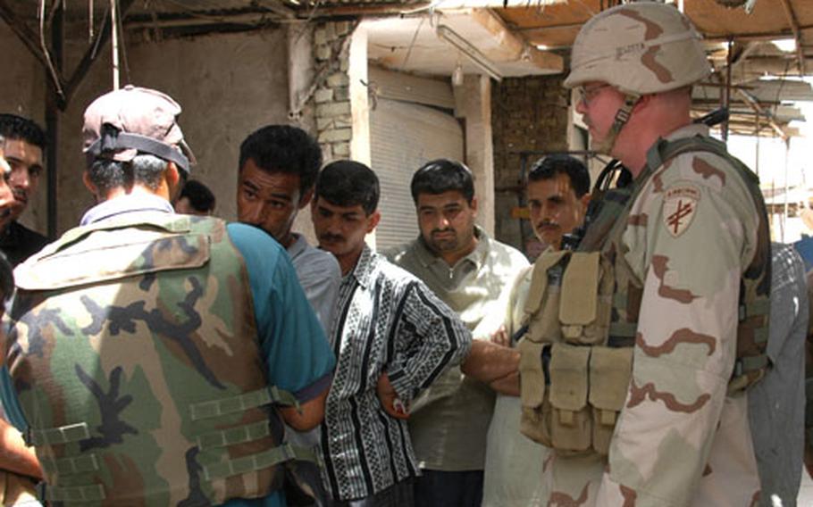 Hussein Ali discusses the need for jobs and electricity with a translator who goes only by Salam, (back to the camera) and Maj. Craig Lester of the 489th Civil Affairs Battalion at a market in south Baghdad.