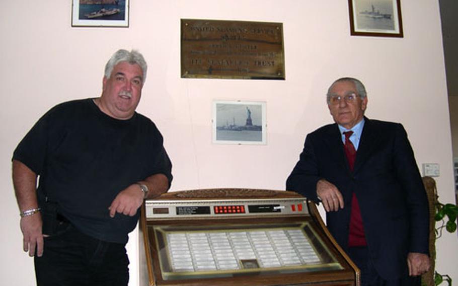 United Seamen&#39;s Service Center director Bill Moerler, left, and long-time employee Daniele D&#39;Ettore lean against the center&#39;s jukebox in Naples, Italy. The jukebox, like D&#39;Ettore, has been serving center patrons for more than 50 years. D&#39;Ettore, who&#39;s done everything at the center from doorman to director in his 53 years of service, said that the jukebox has been with the center for as long as he has. The jukebox has original 45s featuring a wide range of music, from Roy Orbison to Michael Jackson.