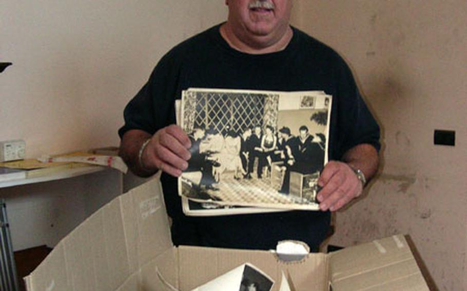 United Seamen&#39;s Service Center director Bill Moerler holds some of the hundreds of old photos taken during the center&#39;s long history in Naples, Italy. Most don&#39;t have any identifying markings or dates, but the large photo he&#39;s holding shows sailors from the aircraft carrier USS Coral Sea. The center closed last month after 50-plus years of service.