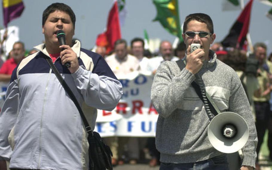 A pair of protesters leads the crowd in a series of chants on Sunday outside Naval Station Rota, Spain.