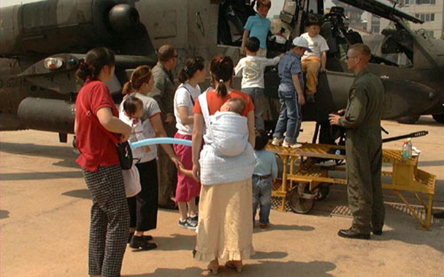 During an open house at Walker Army Heliport in Taegu, South Korea, last May, Korean kids have fun on an AH-64A Apache attack helicopter. Welcoming them were Chief Warrant Officer Josh Hilewitz (left) and Chief Warrant Officer Michael Robertson (right), both of Troop A, 1st Squadron, 6th Cavalry Brigade, out of Camp Eagle, Korea.