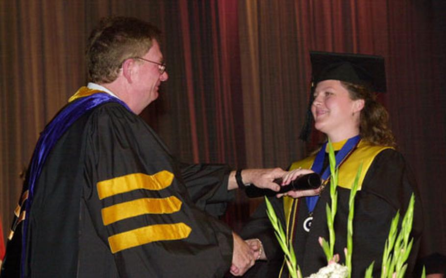 Kristina Broussard receives her diploma Sunday from Gary Hunt, director of University of Maryland University College - Korea.