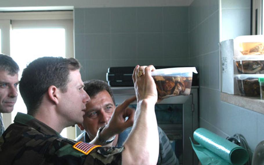 Capt. Eric Lombardini, the Army veterinarian at Aviano Air Base, Italy, shows Slovenian army Col. Peter Levstek, center, a specimen from the clinic Wednesday during a tour of the facility. Slovenian Maj. Darko Semrov looks on.