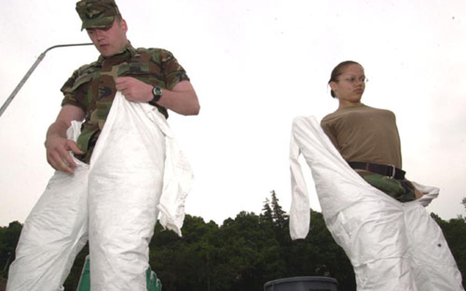 Decontamination members, Spc. Sky Laron, left, and Spc. Jamie Moore, from U.S. Army Japan, get dressed in chemical protective suits at the start of a Chemical, Biological, Radiological, Nuclear and High Explosive Situational Exercise at Camp Zama on Wednesday.