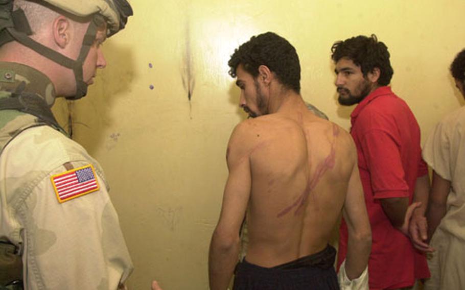 A military policeman examines the whip scars on an Iraqi prisoner&#39;s back Friday morning following a raid at a police station in Sabi Abor, Iraq.