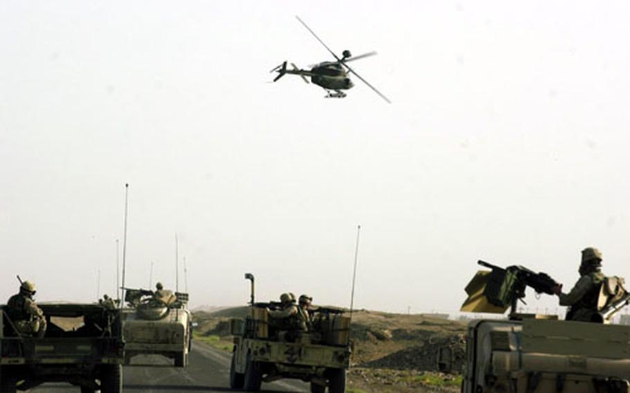 A Kiowa helicopter flies in low over Humvee guntrucks just outside Sabi Abor, Iraq.