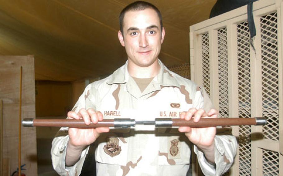 Senior Airman Andrew Hairell, a customs border clearing agent at the amnesty point on Camp Wolverine, displays a baton that separates into two swords. Swords are considered contraband. All servicemembers leaving from a deployment through Camp Wolverine are completely inspected for illegal items prior to departure.