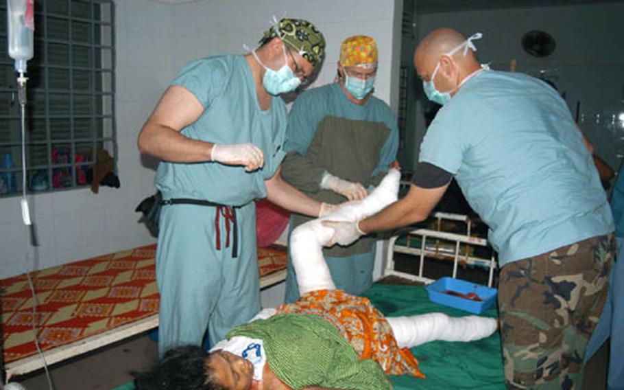 U.S. Air Force Capt. Jason Rosenberg, left, Lt. Col. Jim Walter, center, and Master Sgt. Kristopher Krenzke bandage the legs of a Cambodian burn patient Thursday during the BRAVA 2004 medical mission to Kep, Cambodia.