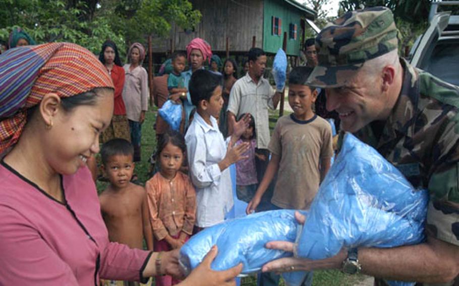 Air Force Tech. Sgt. Bryan Gray hands out mosquito nets to a Cambodian woman in a small village near Kep, Cambodia, Thursday. Gray is a biomedical equipment repair technician with the 18th Medical Support Squadron at Kadena Air Base, Okinawa. He&#39;s part of a 20-member team participating in BRAVA 2004.