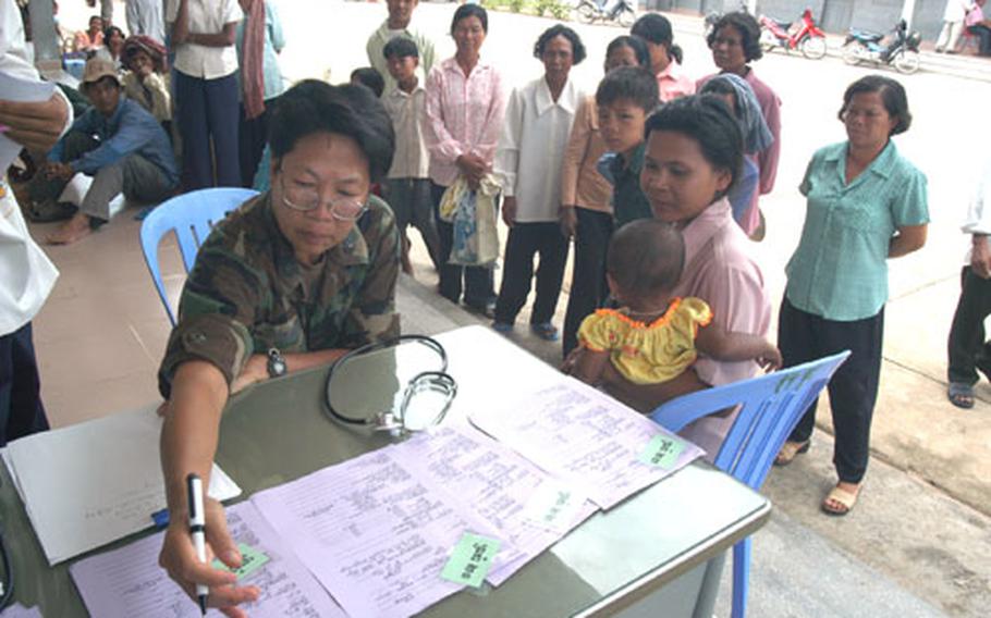U.S. Air Force Lt. Col. Diep Duong looks over a patient&#39;s screening paperwork as she assesses possible patients in a hospital compound in Kep. Duong is a nurse normally assigned to Det. 2, 13th Air Force International Health Specialist Program at Hickam AFB, Hawaii.