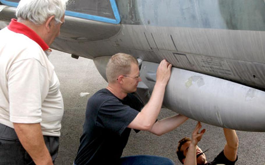 Giovanni Follador, who runs an air museum in Pordenone, watches as Capt. Ed Eisenhauer, left, and 1st Lt. Andrew Wojtalewicz try to take off a panel of the Hawker Hunter fighter jet that will soon grace Follador’s museum.