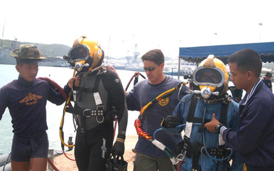U.S. Navy divers prepare to enter the water with a Thai diver at Sattahip Naval Base, Thailand.