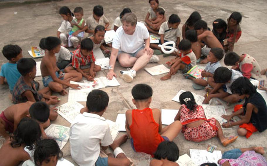 Air Force Master Sgt. Rita Greiner leads a coloring book session with Cambodian children in a hospital compound in Kep. Sergeant Greiner is an orthopedics technician on a 20-member blast resuscitation and victim assistance mission - also known by medics as BRAVA - sponsored by the U.S. military&#39;s Pacific Command.