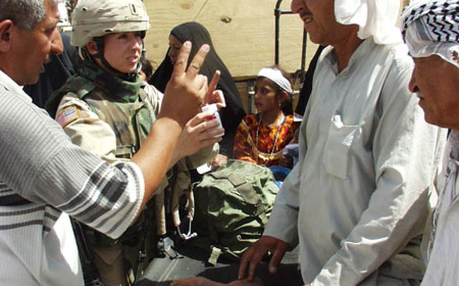 First Lt. Robin Lowery of Little Rock, Ark., a physician&#39;s assistant with Company, 39th Medical Group, tells a man through an interpreter about his medical treatment during a visit Saturday to Mushada, Iraq. Lowery was part of an Army convoy that made a goodwill trip to the small village located about 30 miles north of Baghdad.