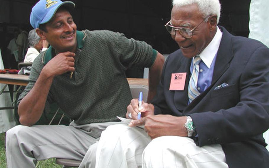 Buck O&#39;Neil, right, a World War II veteran who played baseball in the Negro Leagues and was the first African-American coach in the majors, signs an autograph for an admirer Sunday at the National World War II Reunion.