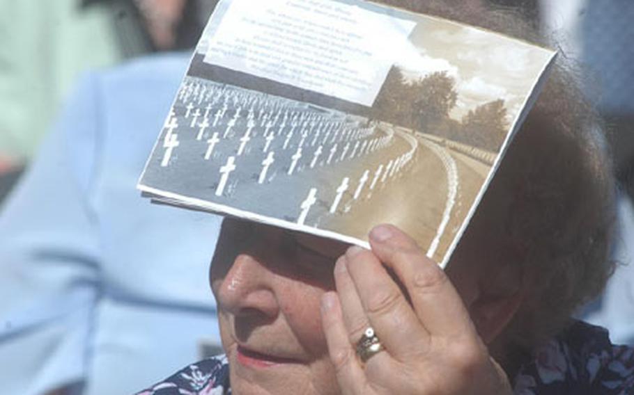 A woman uses a program to shade her eyes during the Memorial Day ceremony Monday at Cambridge American Cemetery in Madingley, England.