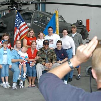 Scott Rouch, of the 98th Area Support Group Public Affairs Office, snaps a photo of concertgoers with Toby Keith, sitting in the front row, in Illesheim, Germany, in 2004. The crew rushed groups of people through to accommodate the long line of fans wanting to have their pictures taken with the country music star. 