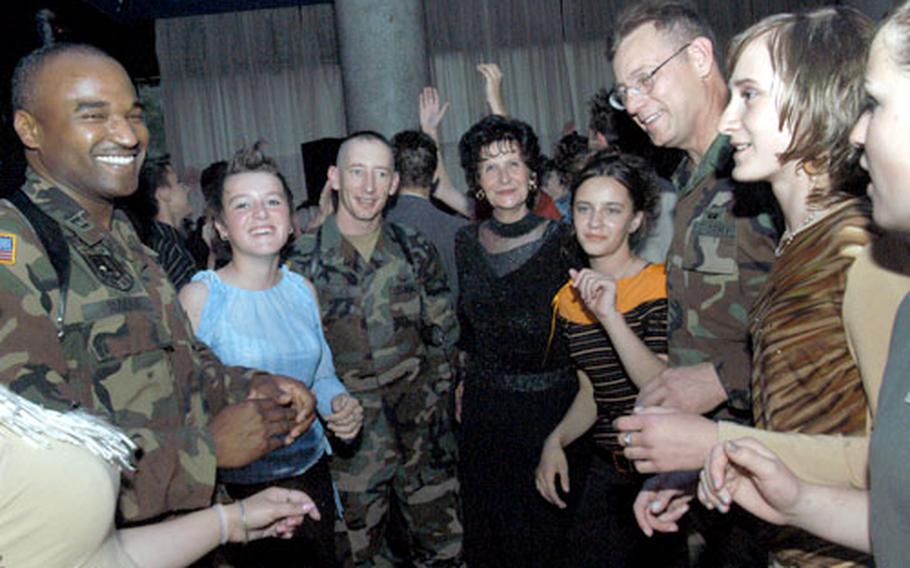 Capt. David Rader, left, Sgt. 1st Class Chris Wallace and 1st Sgt. David Jordan, all of Task Force Raptor, dance with the students of Bokovici Elementary School and their teacher, Jasminka Halilagic, at the students’ mini-graduation in Lukavac, Bosnia and Herzegovina, on Saturday evening. The task force has sponsored Bokovici and nine other schools and were invited by the students and teachers to celebrate eighth-grade graduation.