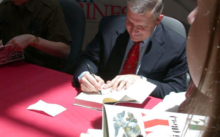 Retired Marine Gen. Anthony Zinni, right, former commander of U.S. Central Command, signs copies of his new book, "Battle Ready," written with renowned author Tom Clancy, left, outside Marine Corps Base Quantico, Va. The pair signed more than 600 books Wednesday.