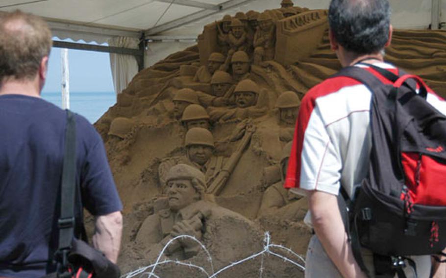 Two visitors look at a sand sculpture at Vierville-sur-Mer, France.