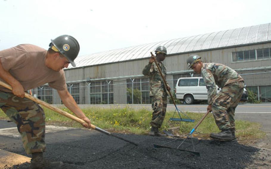 From left, Petty Officer 2nd Class Paul Torres, Constructionman Cedric Park and Petty Officer 3rd Class Arlo Capelle from Naval Mobile Construction Battalion 5 Detail Atsugi, use a shovel and rakes to level asphalt for a flight line running track project Thursday at Atsugi Naval Air Facility, Atsugi.